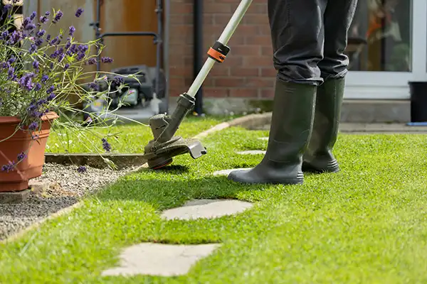 A landscaper performing some edging work on a walkway surrounded by grass
